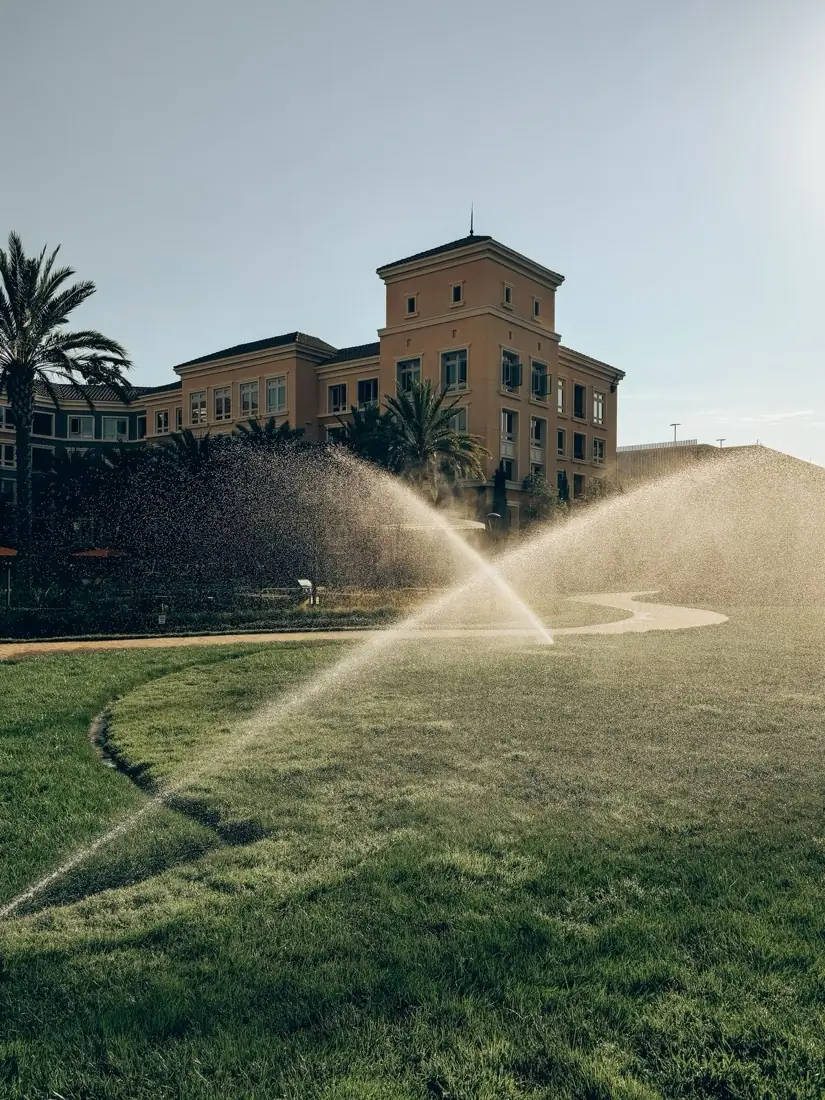 Irrigation sprinklers watering a large green lawn in the morning